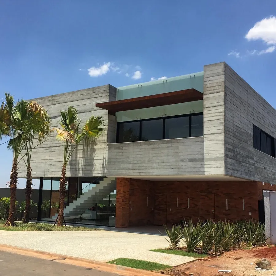 Casa com fachada de placas de concreto e escada interna aparente