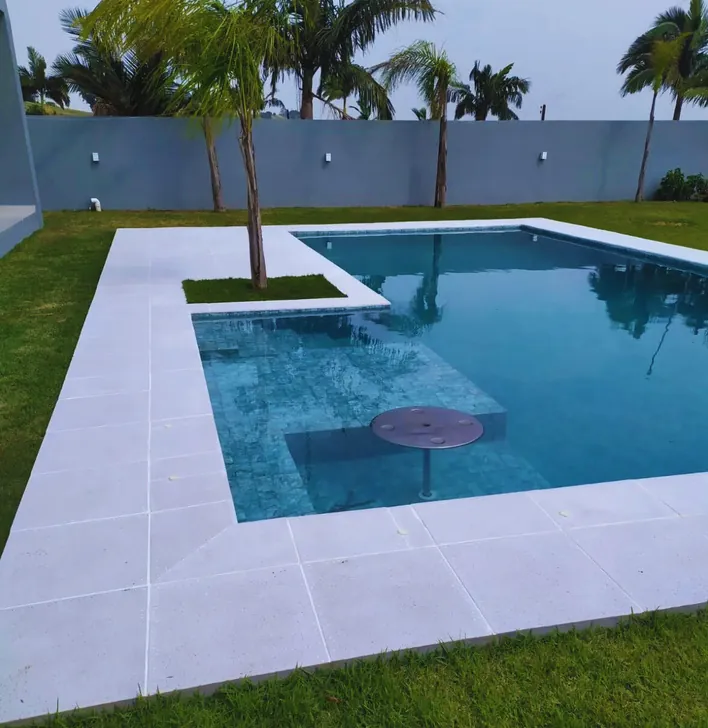 Borda de piscina com piso claro e gramado ao fundo